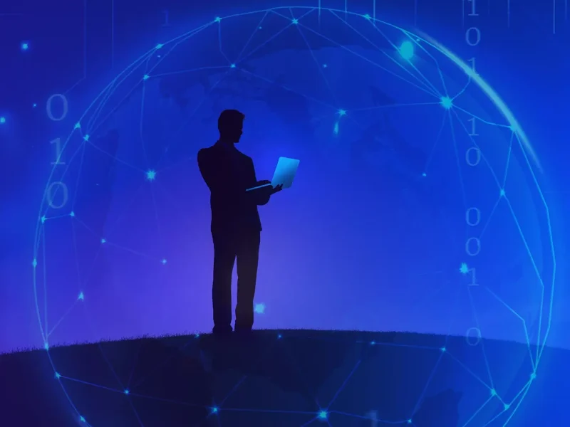 silhouette of a man with a lap top and a blue background with a digital globe